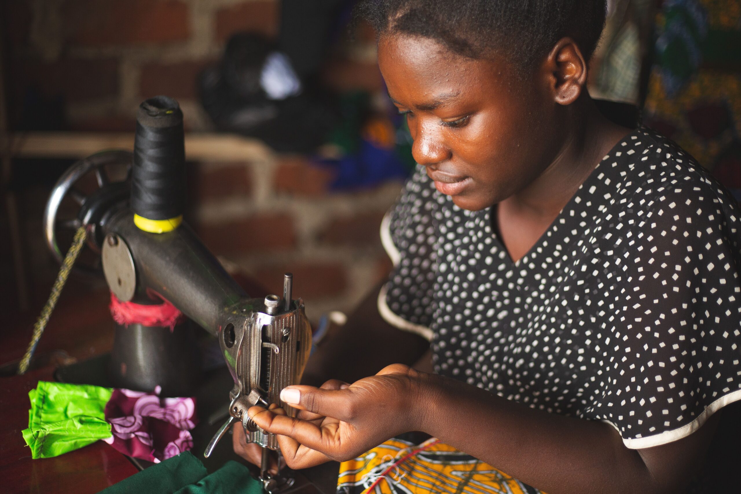A young seamstress focuses on sewing in a workshop in Kasese, Uganda.