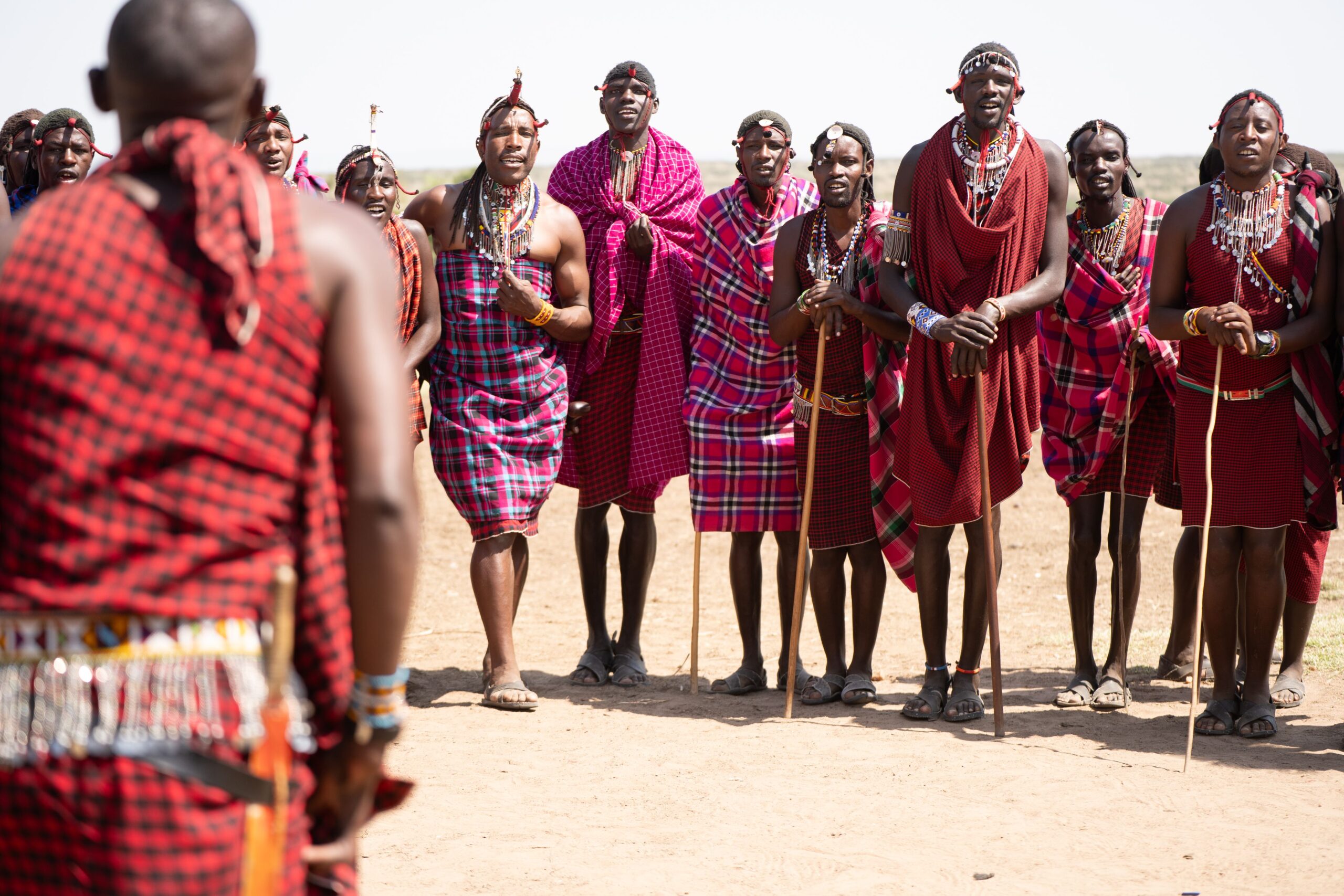 Maasai tribe members in colorful attire singing in the open plains of Kenya.