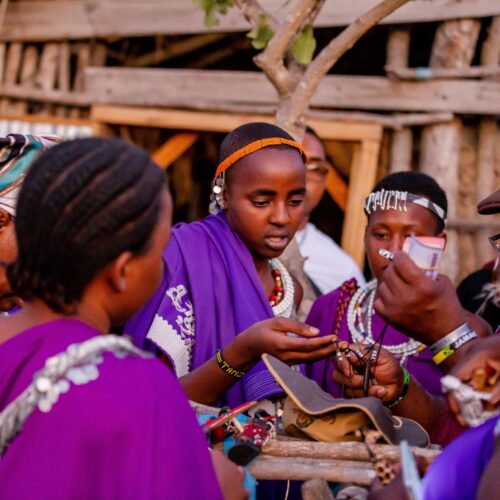 Maasai women in colorful attire engage in cultural activities in Mikumi, Tanzania.